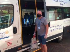A masked man standing next to a minibus.